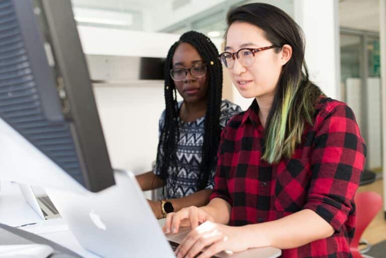 Two women collaborating in front of a laptop – symbolizing tech career coaching support